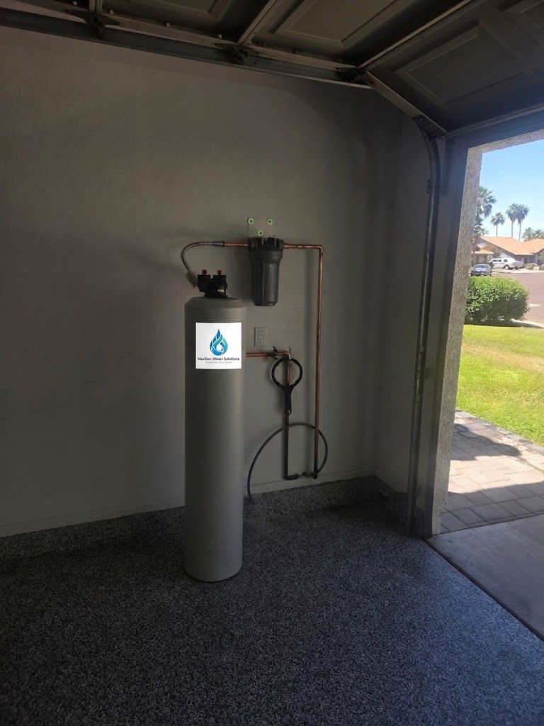 A NexGen filtration tank standing in a carpeted garage beside an open garage door, connected overhead to copper piping and a filter housing.