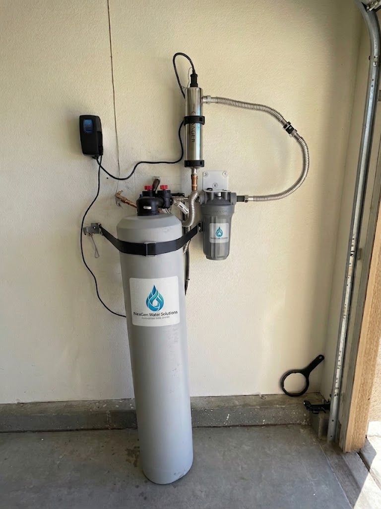 A NexGen whole-home filtration tank in a garage, with an ultraviolet steriliser and a clear-bowl pre-filter mounted on the wall above it.