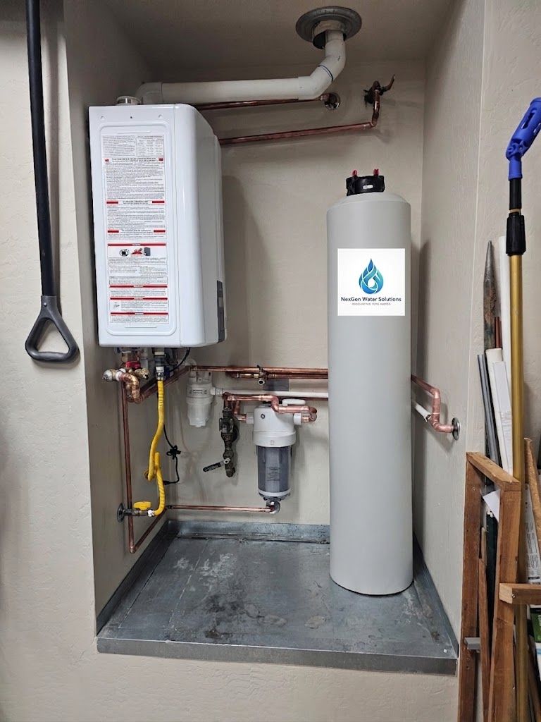 A NexGen filtration tank installed in a utility closet next to a tankless water heater, with copper supply lines and a filter housing between them.